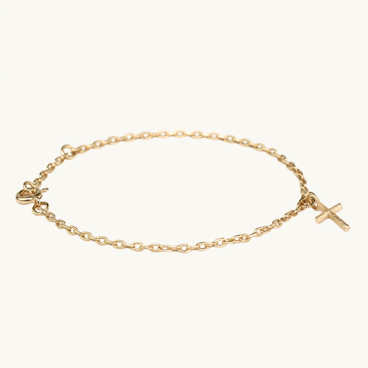 Armband i guldfrgylld mssing med en kors berlock