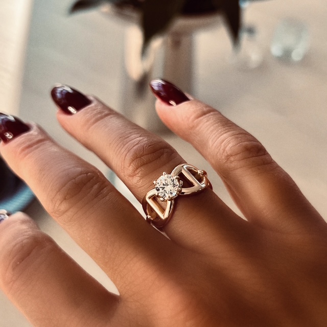 En guldring med ankarmönster och en vit diamant