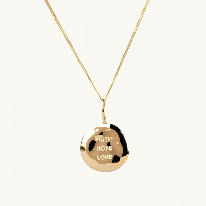 Ett mynt i guld med bucklig yta och texten faith, hope, love