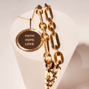 Ett guldmynt med texten faith, hope, love tillsammans med en chunky chain i guld