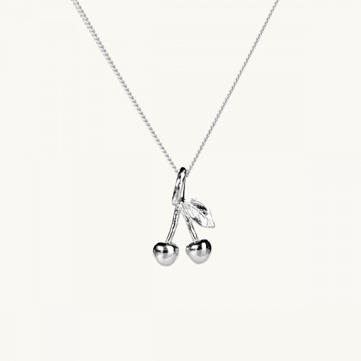 Ett silverhalsband med en berlock i form av två körsbär, med ett blad